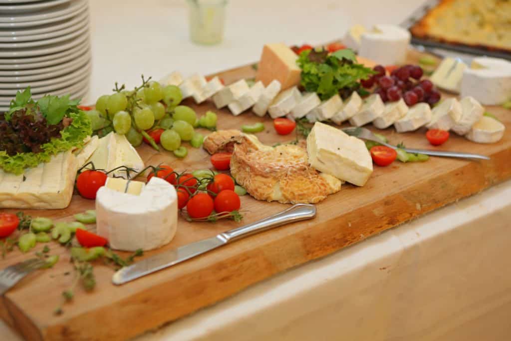 cheeseboard with grapes and tomatoes. A selection of difference cheese on a wooden board 