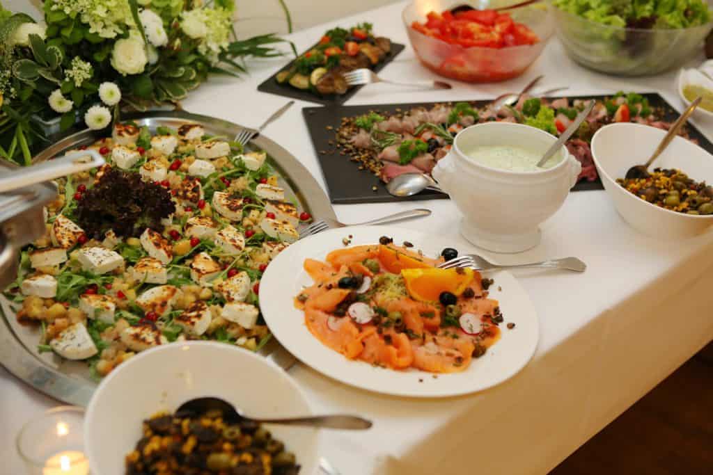 German Wedding Starters - Goatscheese, Smoked Salmon, Horesradish sauce, Selection of salads on a table with white table cloth