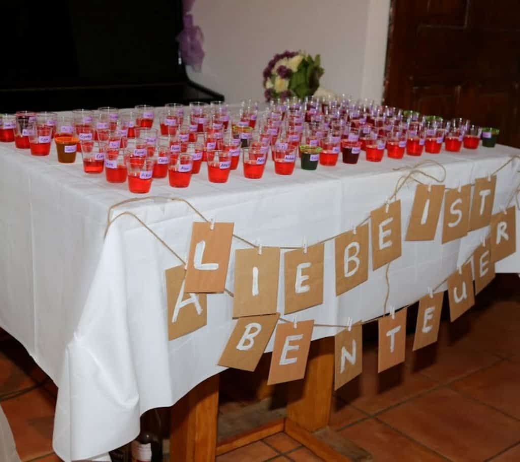 DIY Wedding Seating Chart with Homemade Strawberry Vodka. Underneath there is some signage saying "Liebe ist Arbenteuer" - Love is adventure