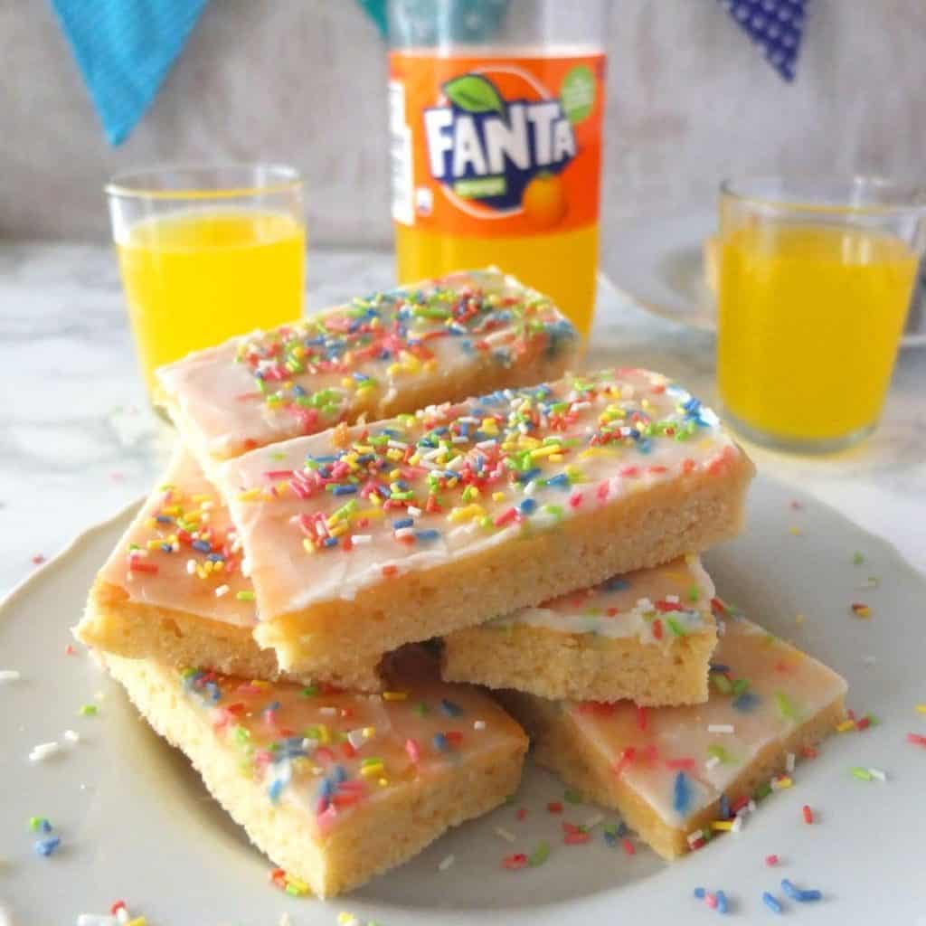 Fanta cake with fanta bottle and glasses in the background 