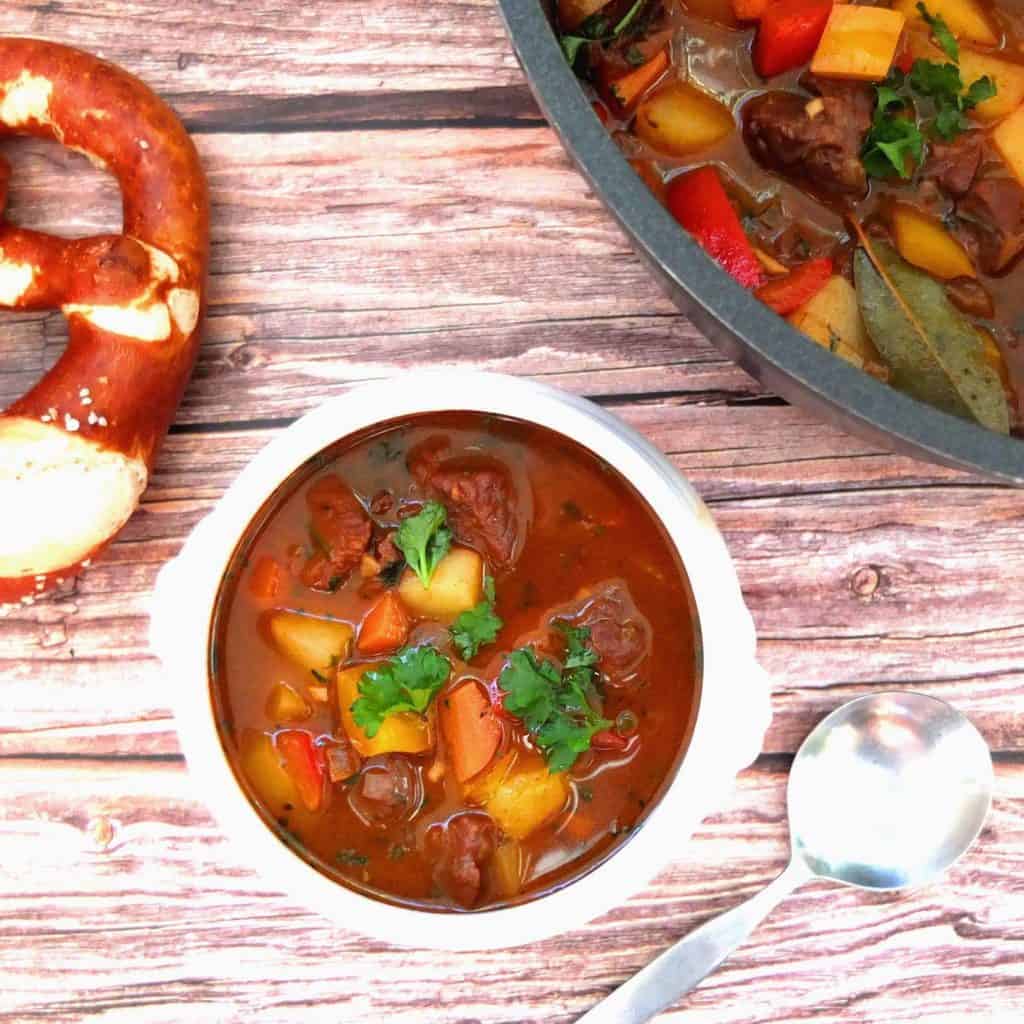 Saucepan, bowl and pretzel with Goulash SOup. 