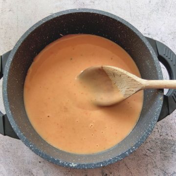 Rahmsauce in a saucepan. A wooden spoon is dipping in