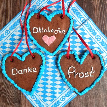 Lebkuchenherzen (German Gingerbread hearts) on a bavarian blue and white napkin. The hearts are decorated with blue icing. The inscription say "Danke (Thank you) "Prost" Cheers" And Oktoberfest