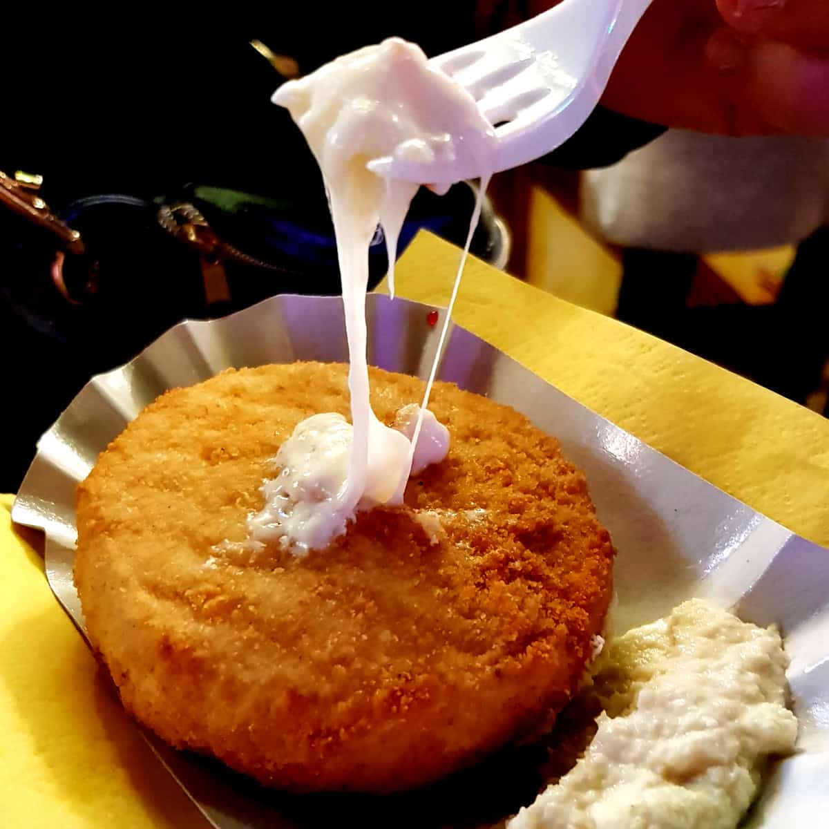 Breaded Camembert at a German Christmas Market. A Fork has dipped into the cheese