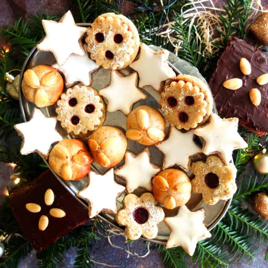 A silver plate with German Christmas Cookies. Spitzbuben, cinnamon stars and Bethmännchen. 