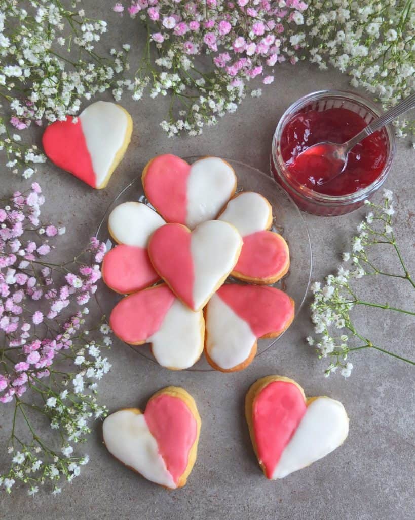 Heart Shaped German cookies, surrounded by flours with a pot of jam.