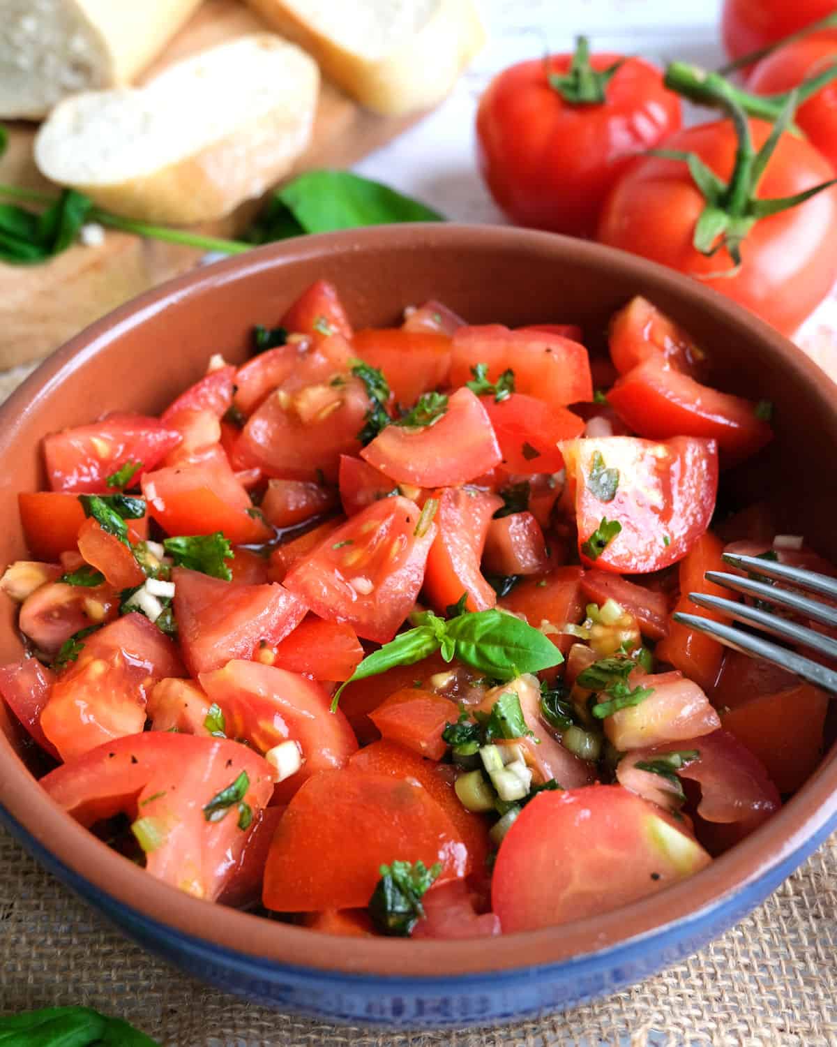 German Tomato Salad with bread and tomatoes in the background.