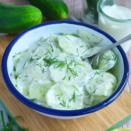 German creamy cucumber salad in a blue and white bowl.