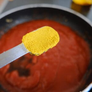 adding curry powder to currywurst sauce