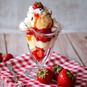 A strawberry sundae with whipped cream and strawberries.