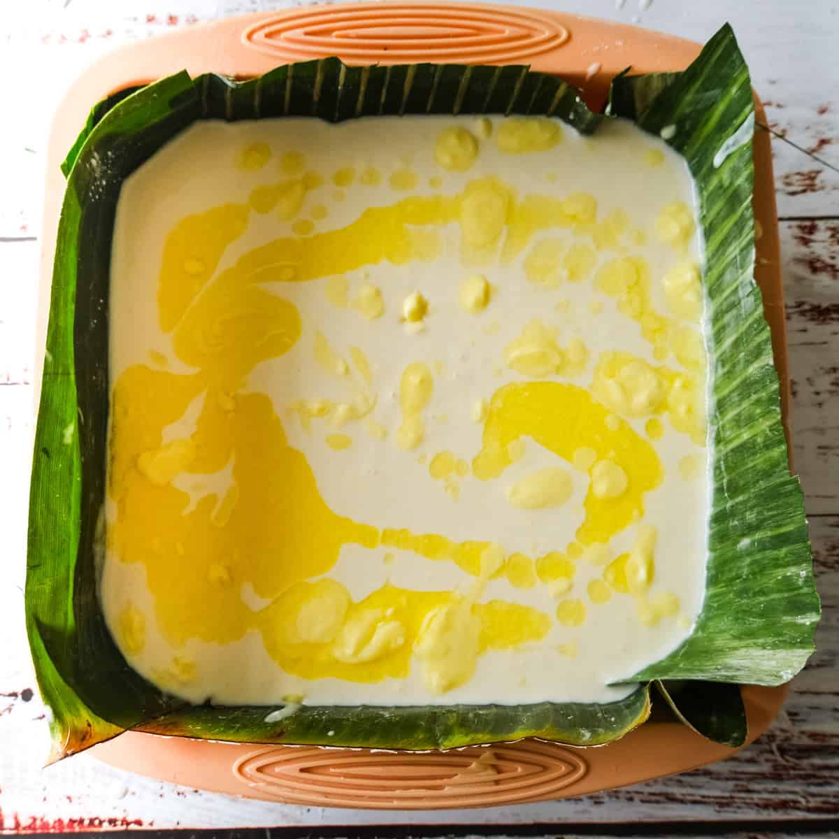 bibinka batter in a cake tin with melted butter on top.