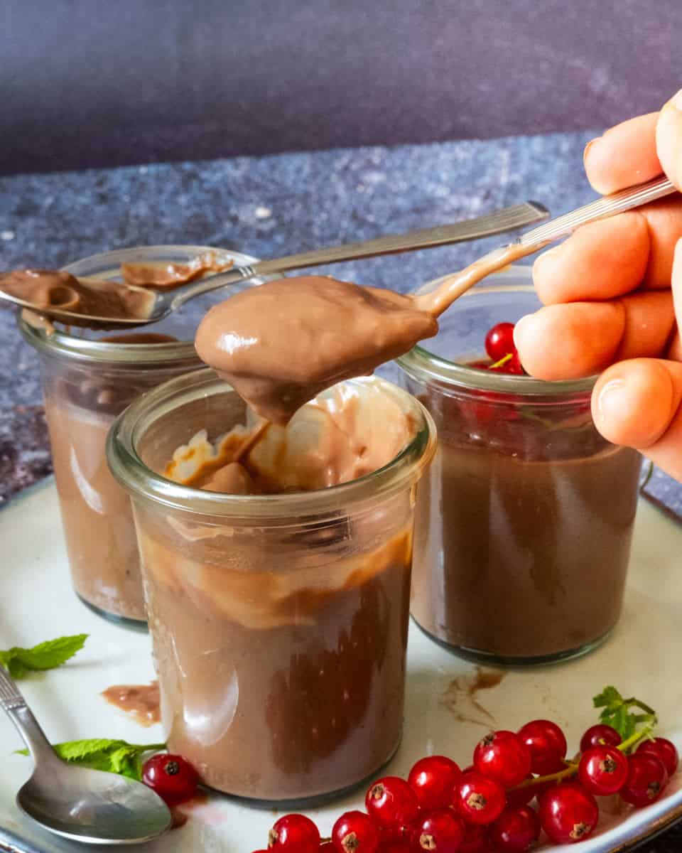 a hand scooping out chocolate pudding from a glas.