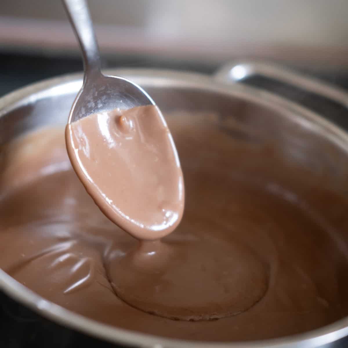 a spoon showing thickened chocolate pudding