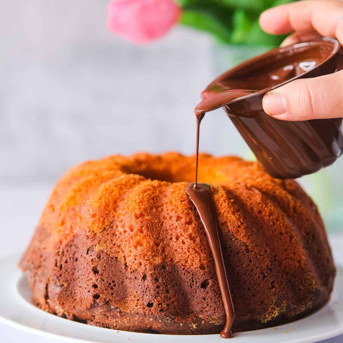 drizzling chocolate over the cake