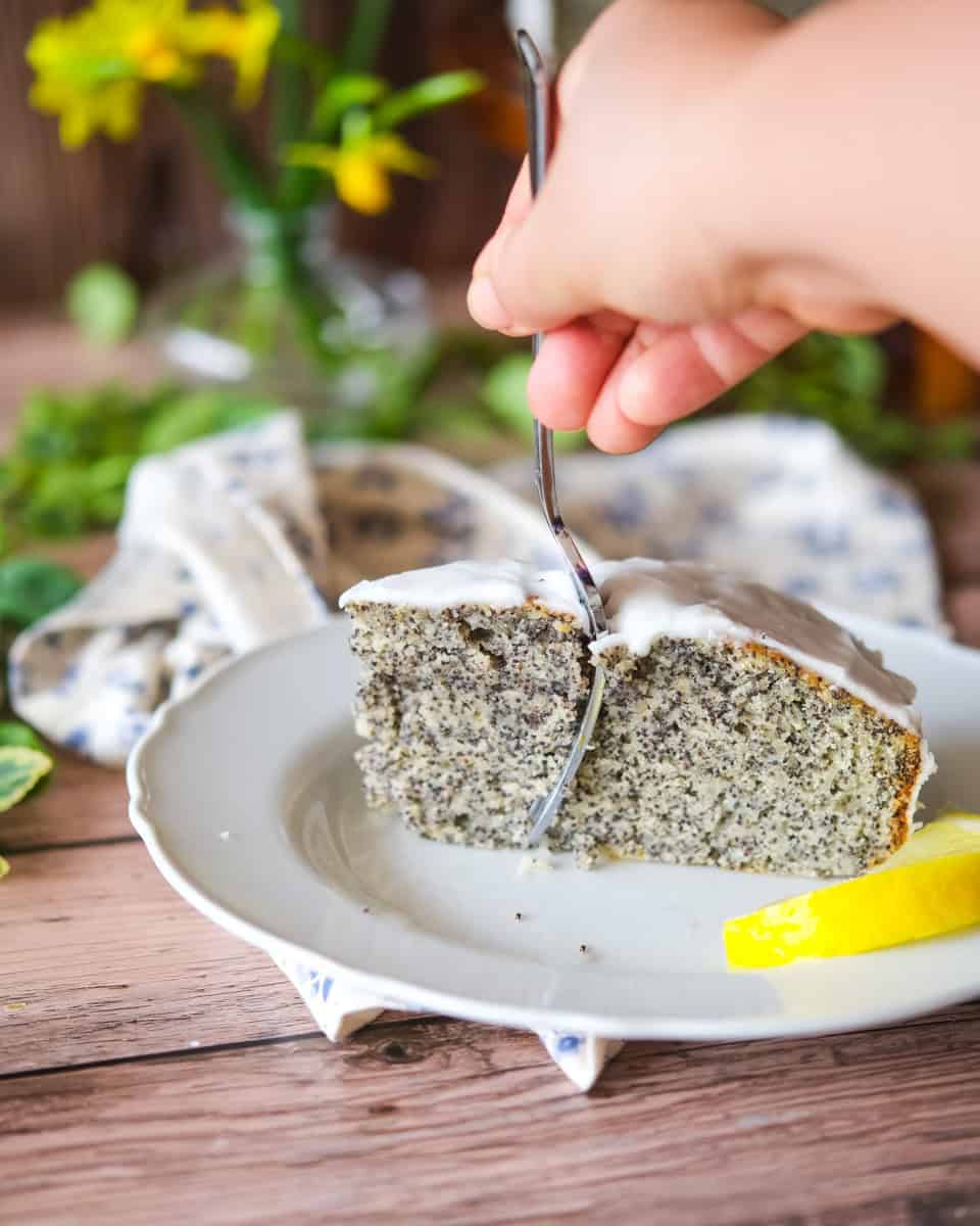 A fork slicing into a lemon poyy seed cake
