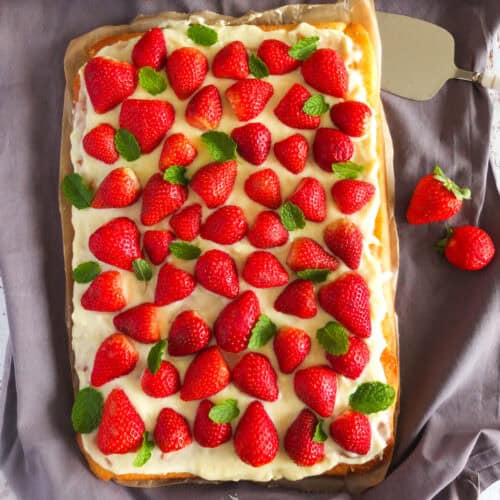 German strawberry cake Erdbeerkuchen on a baking tray with vanilla pudding and fresh strawberries
