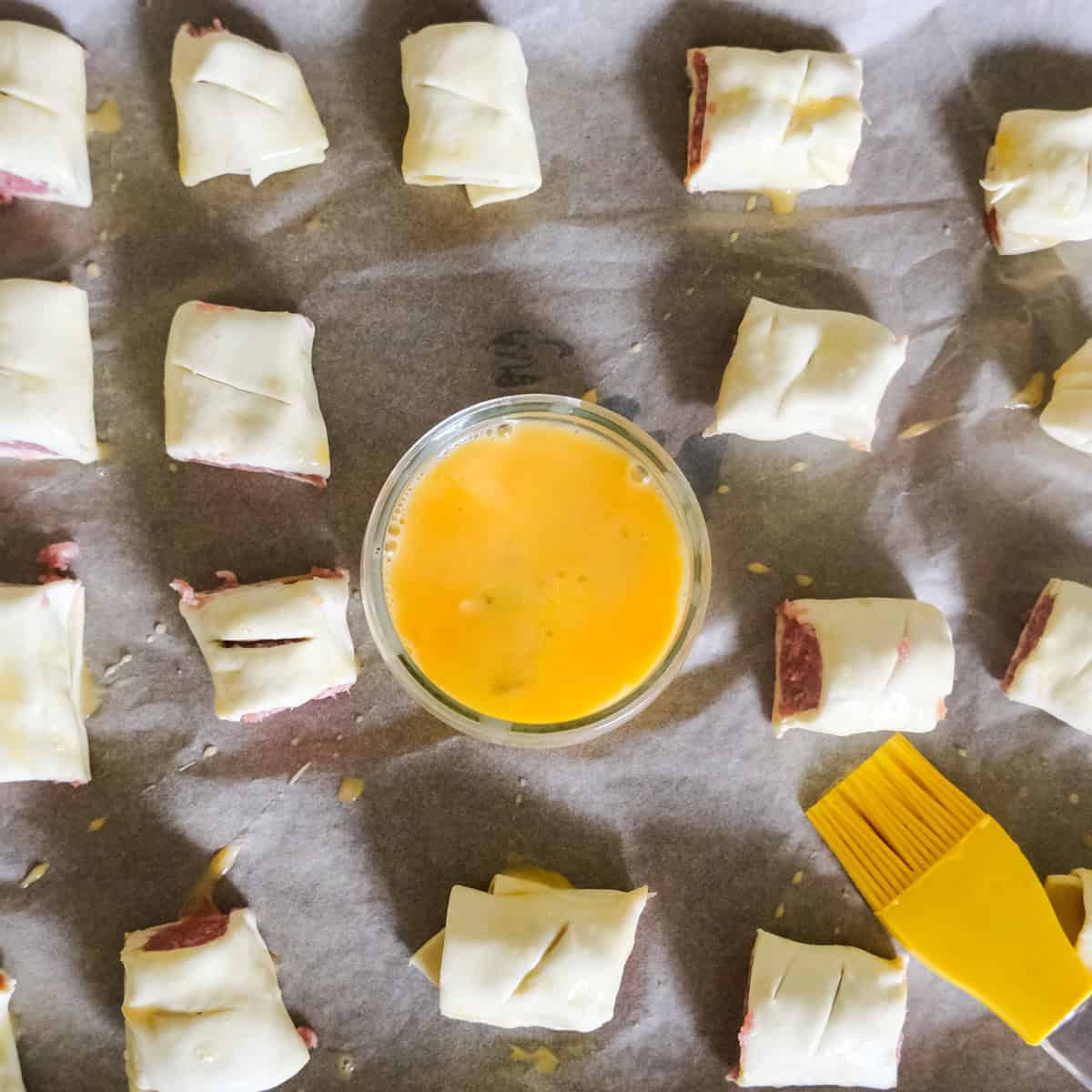 adding egg wash to sausage rolls