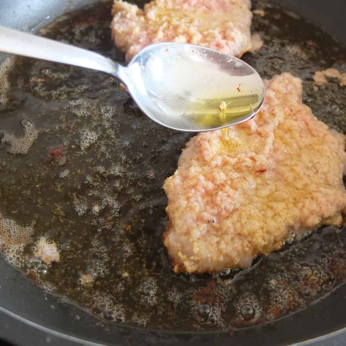 pouring oil over frying schnitzel